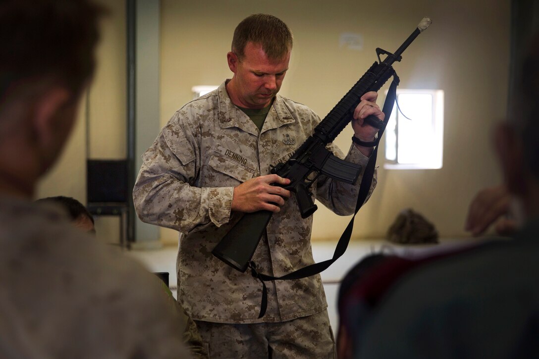 A U.S. Marine shows Afghan National police officers how to perform a functions check on an M16A2.