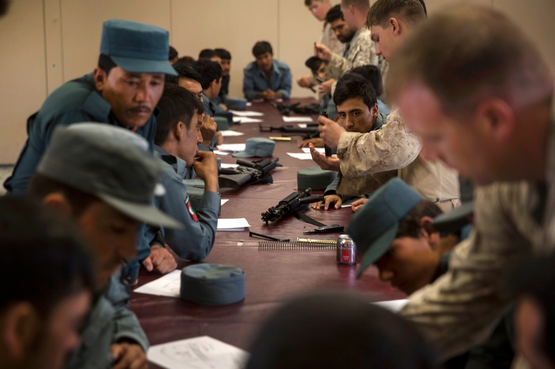 Marines show Afghan National police officers how to disassemble their new M16A2 assault rifles.