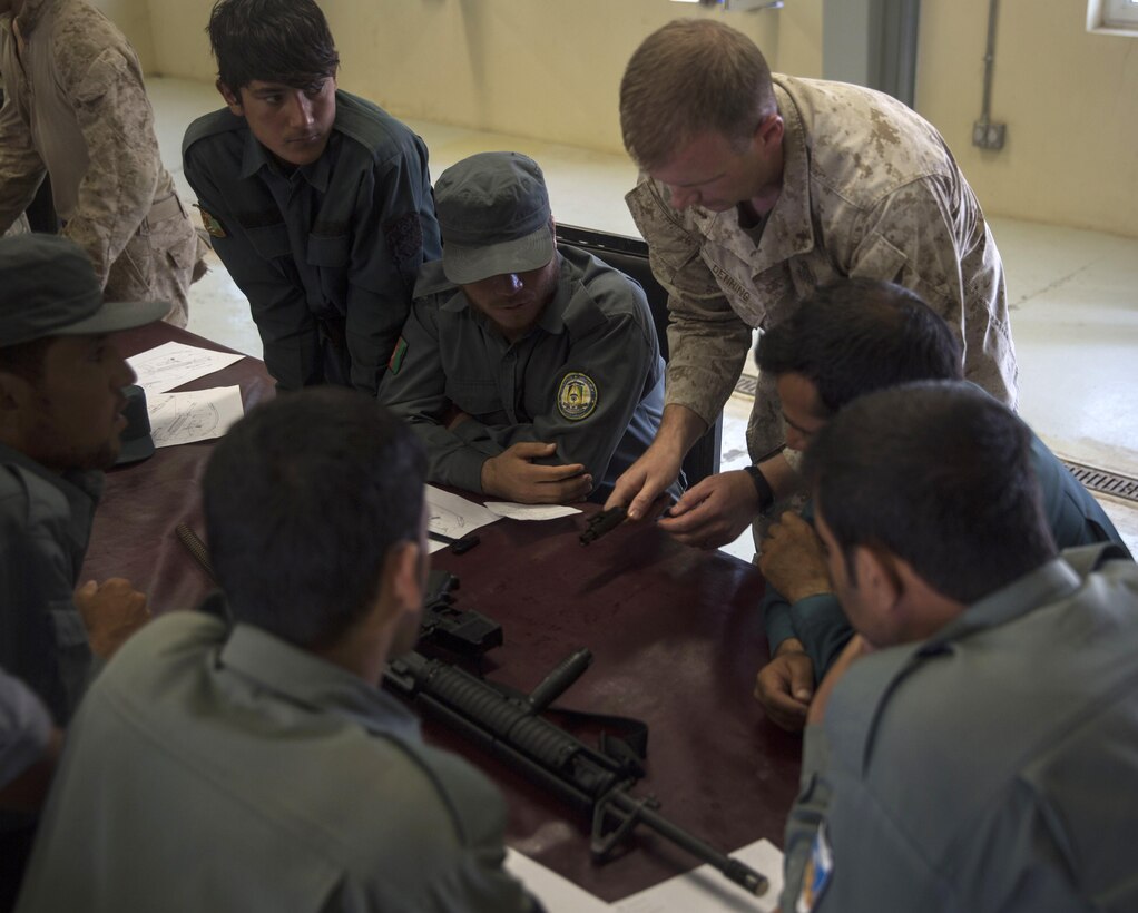A U.S. Marine performs a step-by-step to show the Afghan National police trainees how to reassemble the bolt in an M16A2.