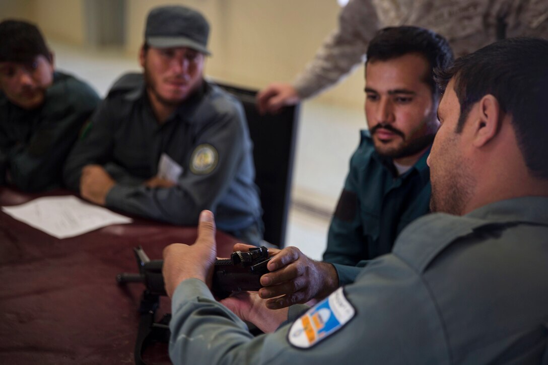 Marine advisors observe an Afghan National police officer reassembling an M16A2 assault rifle
