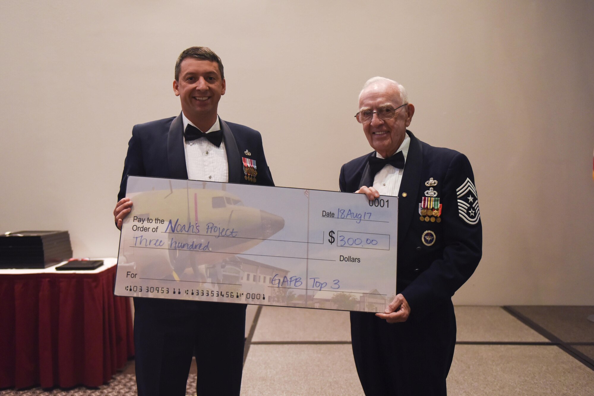 Master Sgt. Douglas Earl, 316th Training Squadron operations superintendent, hands a check to retired Chief Master Sgt. Robert Mehaffey, guest speaker, during the Senior NCO Induction Ceremony at the Event Center on Goodfellow Air Force Base, Texas, Aug. 18, 2017. The check was a donation to Mehaffey’s choice of charity. (U.S. Air Force photo by Airman 1st Class Chase Sousa/Released)