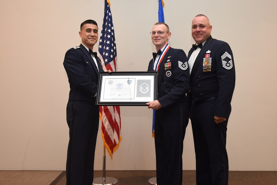 U.S. Air Force Tech. Sgt. Andrew Britt, 316th Training Squadron, receives their certificate of selection from Col. Ricky Mills, 17th Training Wing commander, and Chief Master Sgt. Daniel Stein, 17th Training Group superintendent, during the Senior NCO Induction Ceremony at the Event Center on Goodfellow Air Force Base, Texas, Aug. 18, 2017. (U.S. Air Force photo by Airman 1st Class Chase Sousa/Released)