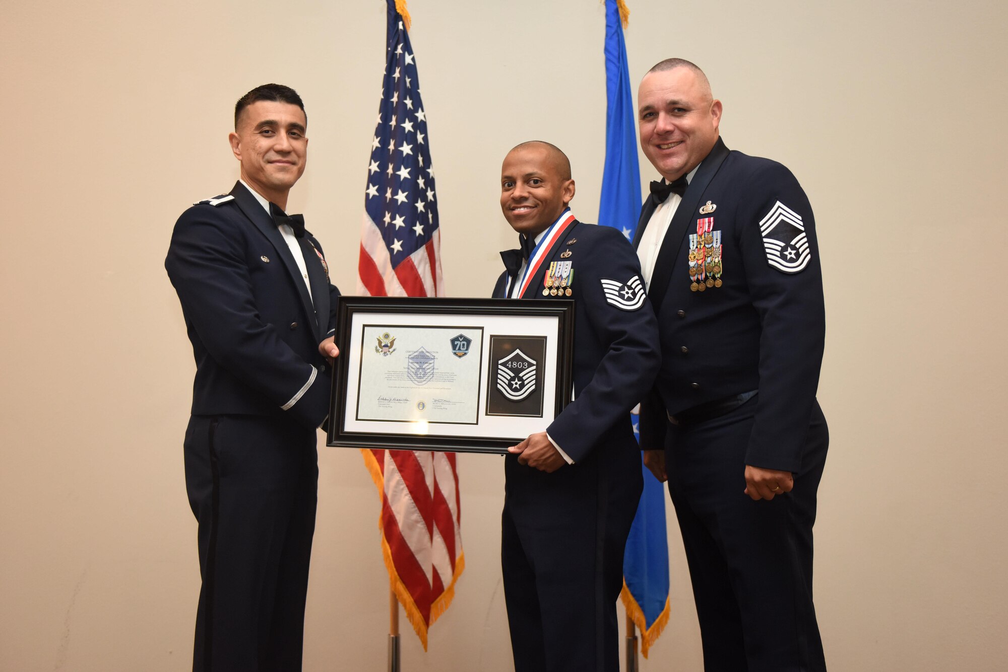 U.S. Air Force Tech. Sgt. Sheraz Cedeno, 17th Civil Engineer Squadron, receives their certificate of selection from Col. Ricky Mills, 17th Training Wing commander, and Chief Master Sgt. Daniel Stein, 17th Training Group superintendent, during the Senior NCO Induction Ceremony at the Event Center on Goodfellow Air Force Base, Texas, Aug. 18, 2017. (U.S. Air Force photo by Airman 1st Class Chase Sousa/Released)