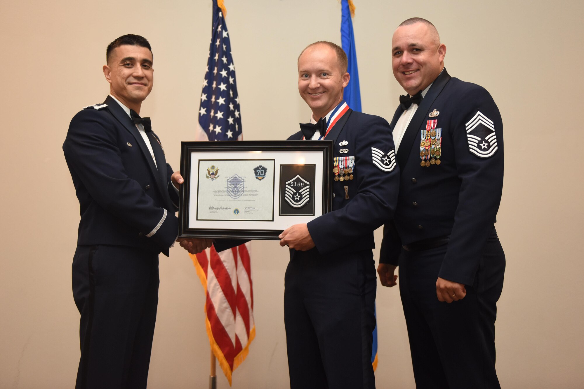 U.S. Air Force Tech. Sgt. Aaron Dvorak, 315th Training Squadron, receives their certificate of selection from Col. Ricky Mills, 17th Training Wing commander, and Chief Master Sgt. Daniel Stein, 17th Training Group superintendent, during the Senior NCO Induction Ceremony at the Event Center on Goodfellow Air Force Base, Texas, Aug. 18, 2017. (U.S. Air Force photo by Airman 1st Class Chase Sousa/Released)
