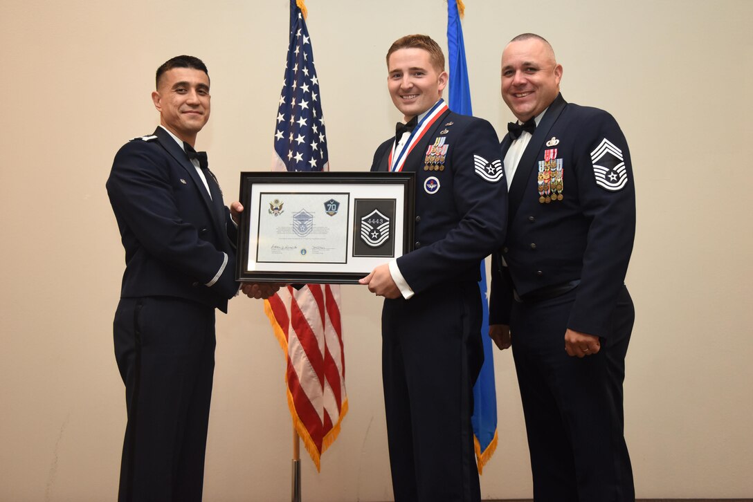 U.S. Air Force Tech. Sgt. Christopher Gibson, 315th Training Squadron, receives their certificate of selection from Col. Ricky Mills, 17th Training Wing commander, and Chief Master Sgt. Daniel Stein, 17th Training Group superintendent, during the Senior NCO Induction Ceremony at the Event Center on Goodfellow Air Force Base, Texas, Aug. 18, 2017. (U.S. Air Force photo by Airman 1st Class Chase Sousa/Released)