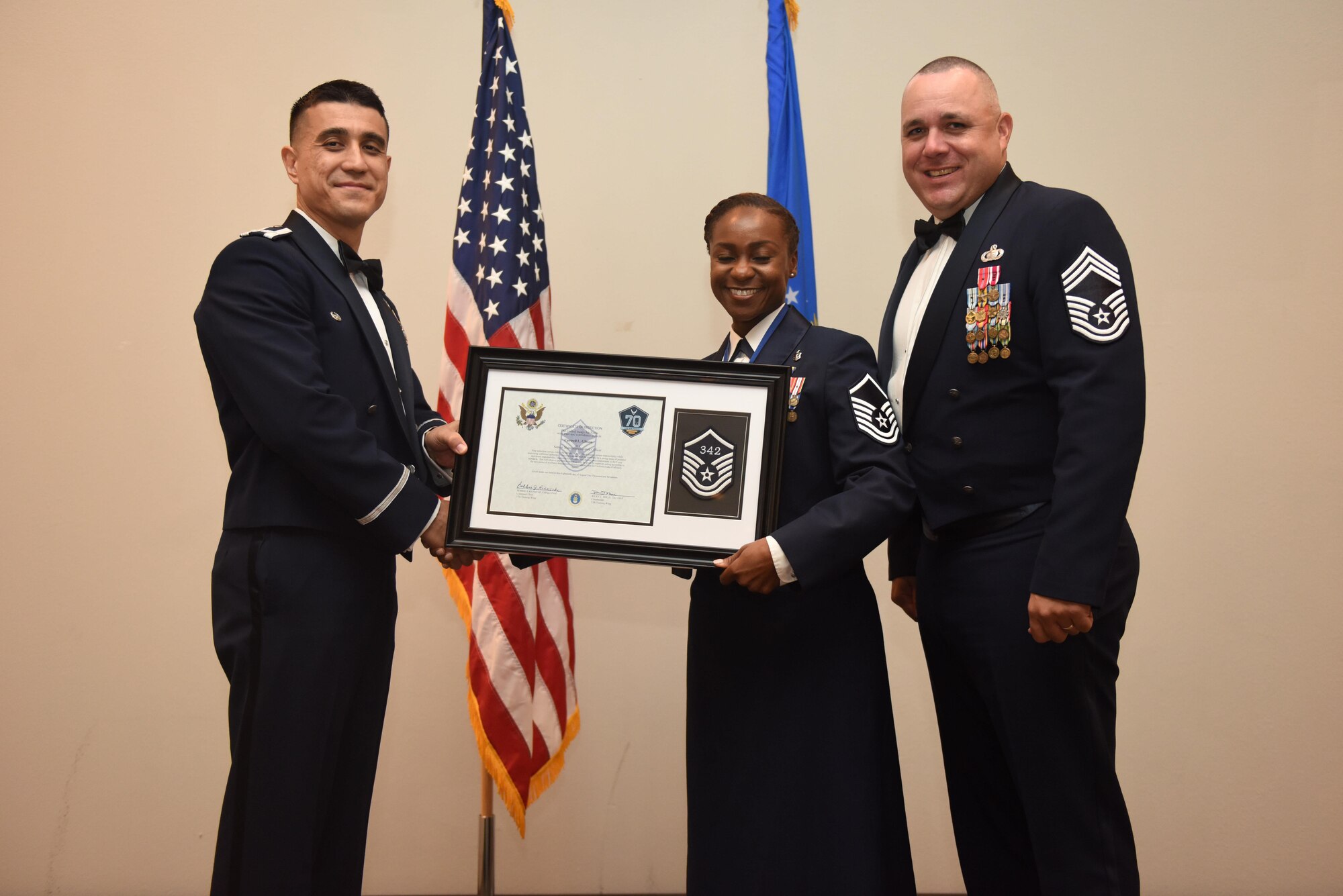 U.S. Air Force Master Sgt. Curtrell Gibson, 17th Force Support Squadron, receives their certificate of selection from Col. Ricky Mills, 17th Training Wing commander, and Chief Master Sgt. Daniel Stein, 17th Training Group superintendent, during the Senior NCO Induction Ceremony at the Event Center on Goodfellow Air Force Base, Texas, Aug. 18, 2017. (U.S. Air Force photo by Airman 1st Class Chase Sousa/Released)