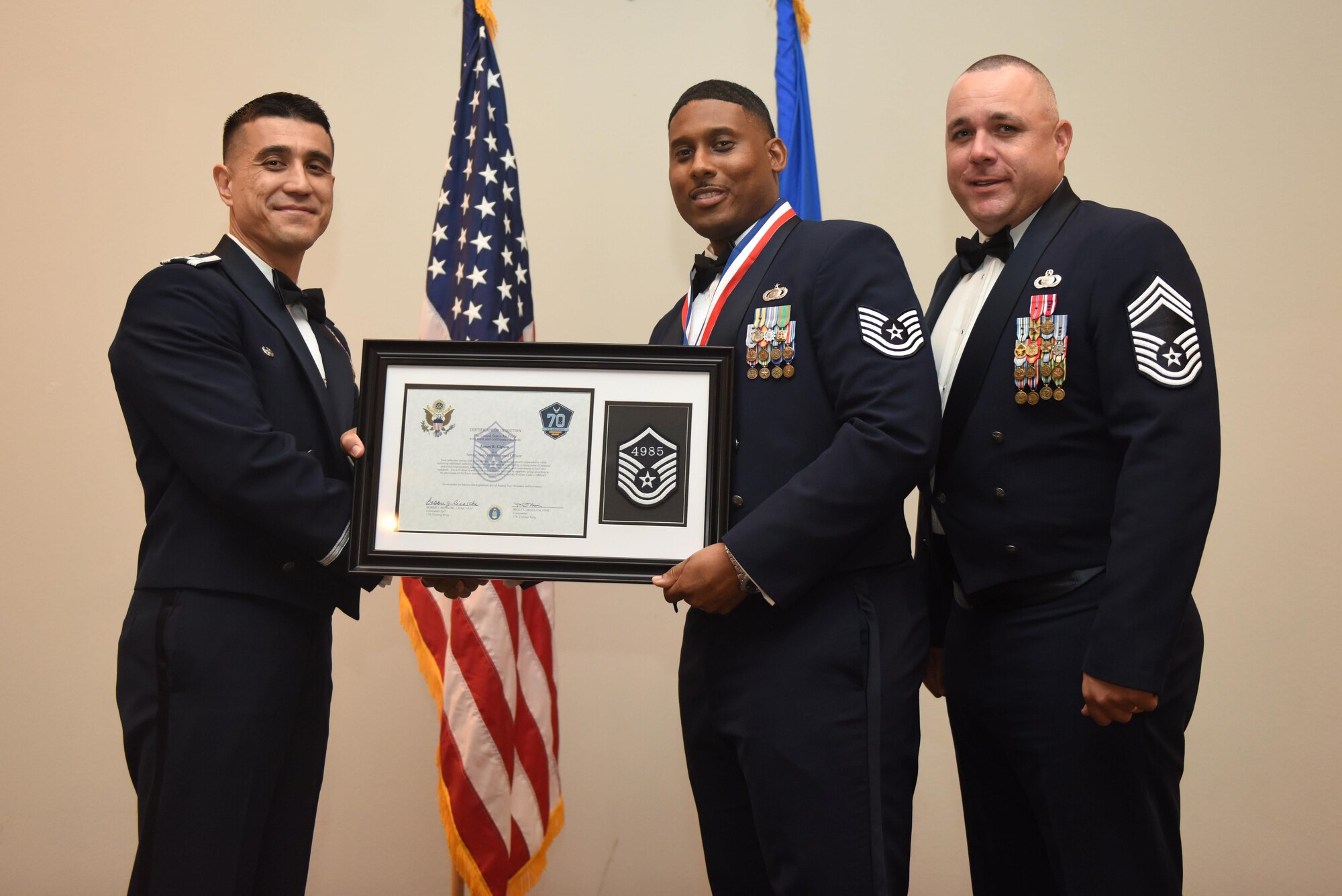 U.S. Air Force Tech. Sgt. James Gipson, 17th Force Support Squadron, receives their certificate of selection from Col. Ricky Mills, 17th Training Wing commander, and Chief Master Sgt. Daniel Stein, 17th Training Group superintendent, during the Senior NCO Induction Ceremony at the Event Center on Goodfellow Air Force Base, Texas, Aug. 18, 2017. (U.S. Air Force photo by Airman 1st Class Chase Sousa/Released)