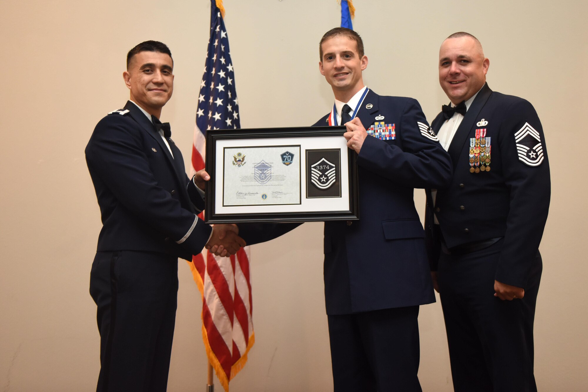 U.S. Air Force Tech. Sgt. Joseph King, 312th Training Squadron, receives their certificate of selection from Col. Ricky Mills, 17th Training Wing commander, and Chief Master Sgt. Daniel Stein, 17th Training Group superintendent, during the Senior NCO Induction Ceremony at the Event Center on Goodfellow Air Force Base, Texas, Aug. 18, 2017. (U.S. Air Force photo by Airman 1st Class Chase Sousa/Released)