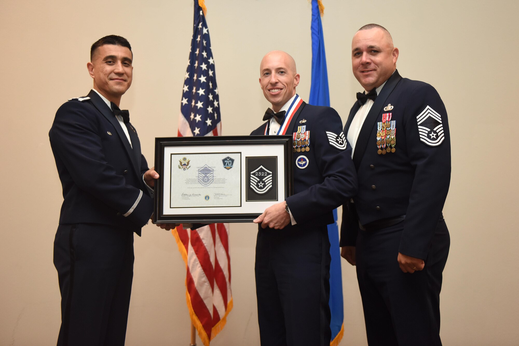 U.S. Air Force Tech. Sgt. Kirtis McCormick, 315th Training Squadron, receives their certificate of selection from Col. Ricky Mills, 17th Training Wing commander, and Chief Master Sgt. Daniel Stein, 17th Training Group superintendent, during the Senior NCO Induction Ceremony at the Event Center on Goodfellow Air Force Base, Texas, Aug. 18, 2017. (U.S. Air Force photo by Airman 1st Class Chase Sousa/Released)