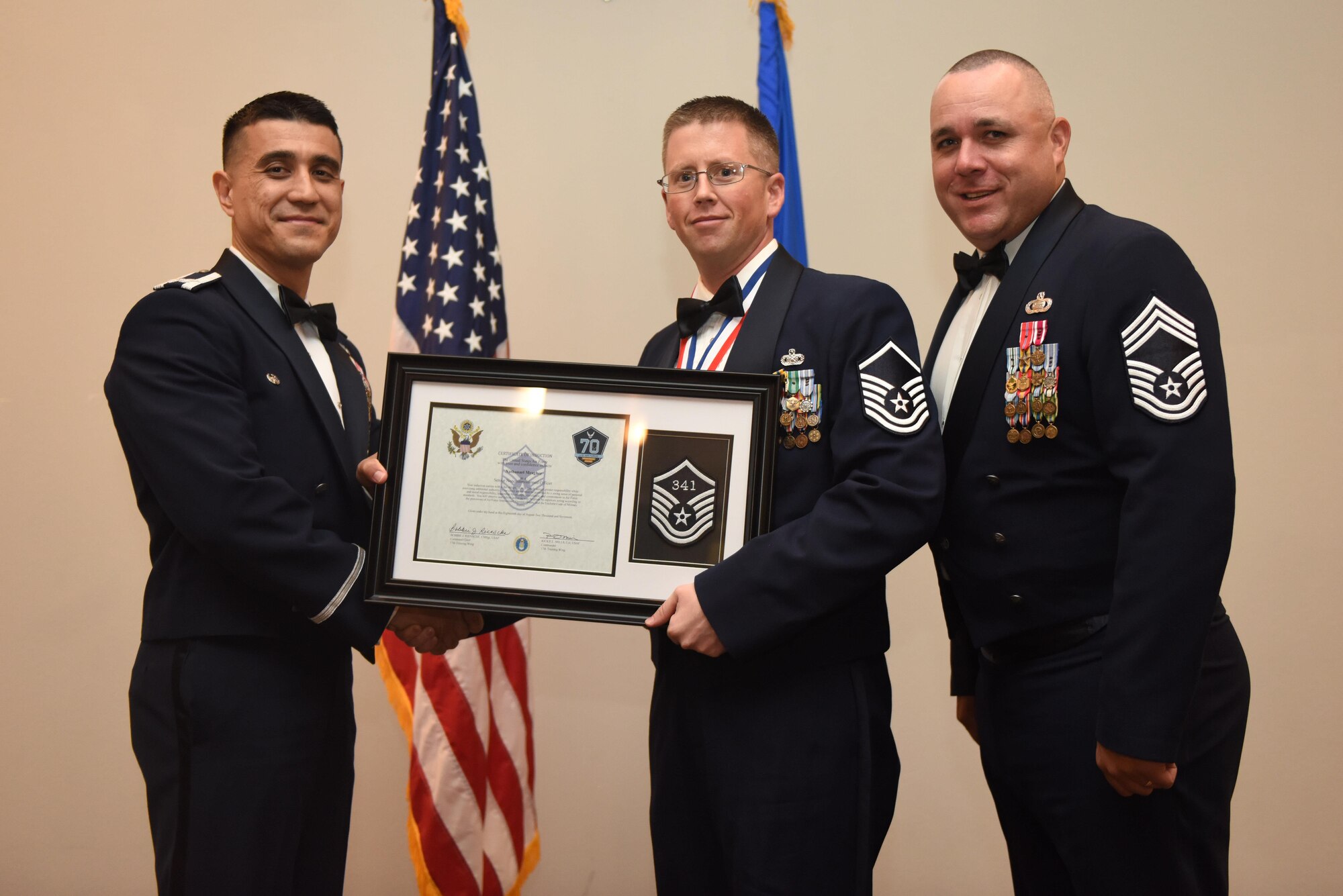 U.S. Air Force Master Sgt. Nathanael Meagher, 17th Force Support Squadron, receives their certificate of selection from Col. Ricky Mills, 17th Training Wing commander, and Chief Master Sgt. Daniel Stein, 17th Training Group superintendent, during the Senior NCO Induction Ceremony at the Event Center on Goodfellow Air Force Base, Texas, Aug. 18, 2017. (U.S. Air Force photo by Airman 1st Class Chase Sousa/Released)