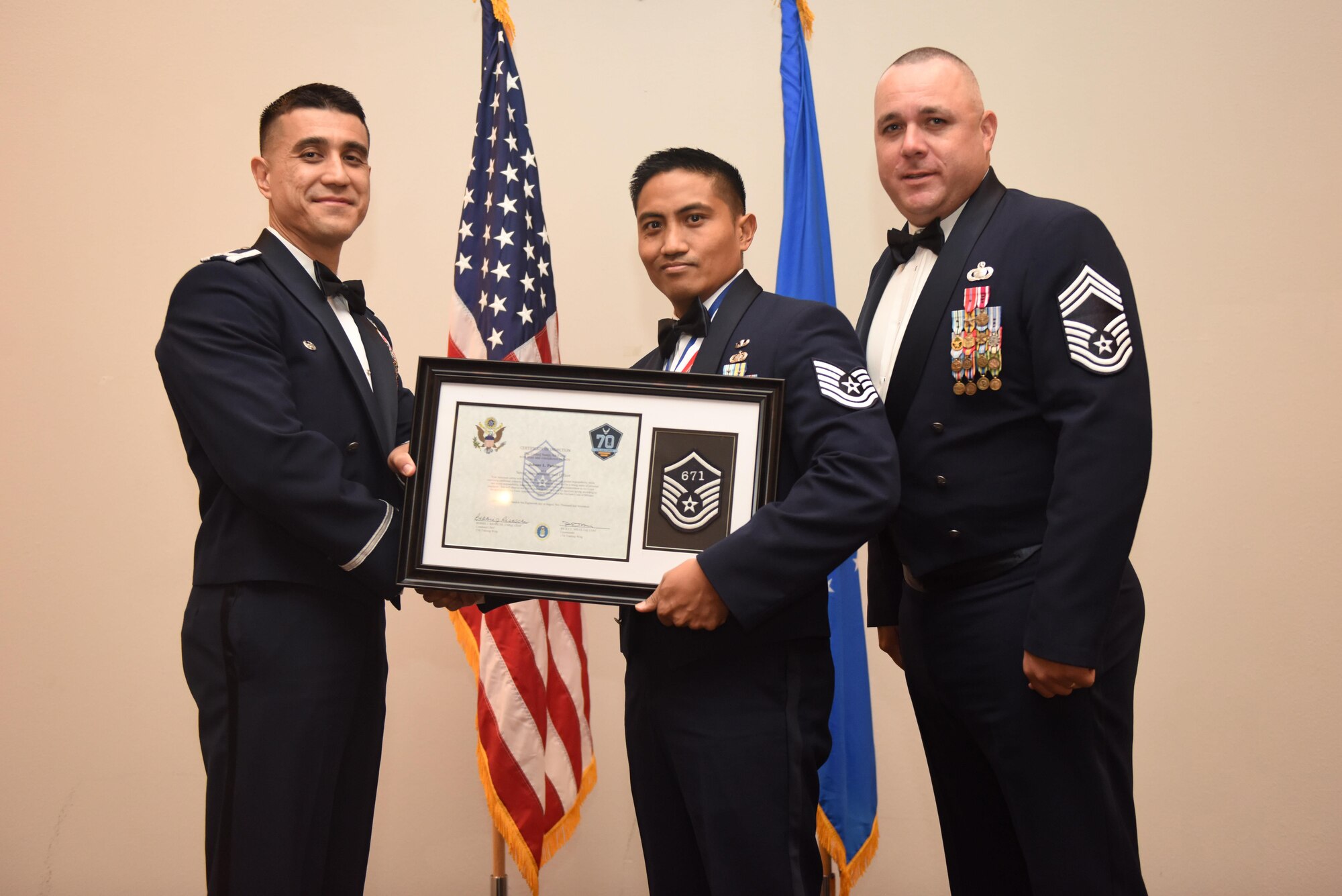 U.S. Air Force Tech. Sgt. Johnny Patubo, 17th Communications Squadron, receives their certificate of selection from Col. Ricky Mills, 17th Training Wing commander, and Chief Master Sgt. Daniel Stein, 17th Training Group superintendent, during the Senior NCO Induction Ceremony at the Event Center on Goodfellow Air Force Base, Texas, Aug. 18, 2017. (U.S. Air Force photo by Airman 1st Class Chase Sousa/Released)