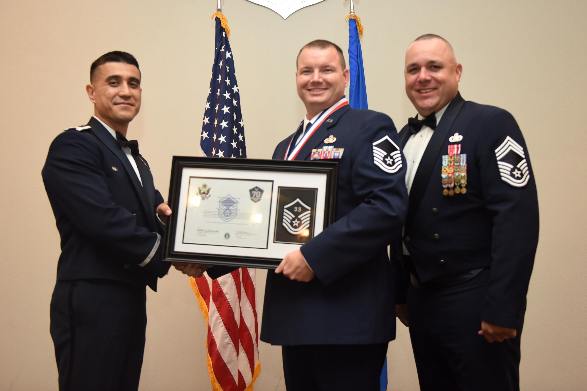 U.S. Air Force Master Sgt. Bruce Perkins, 17th Training Support Squadron, receives their certificate of selection from Col. Ricky Mills, 17th Training Wing commander, and Chief Master Sgt. Daniel Stein, 17th Training Group superintendent, during the Senior NCO Induction Ceremony at the Event Center on Goodfellow Air Force Base, Texas, Aug. 18, 2017. (U.S. Air Force photo by Airman 1st Class Chase Sousa/Released)