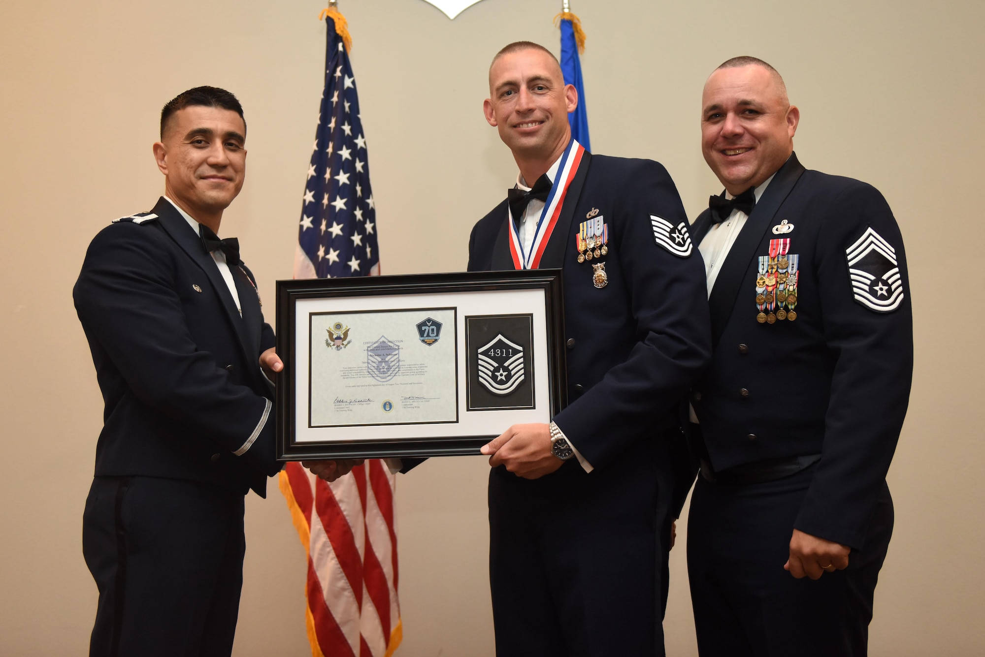 U.S. Air Force Tech. Sgt. Nicholas Schnoes, 312th Training Squadron, receives their certificate of selection from Col. Ricky Mills, 17th Training Wing commander, and Chief Master Sgt. Daniel Stein, 17th Training Group superintendent, during the Senior NCO Induction Ceremony at the Event Center on Goodfellow Air Force Base, Texas, Aug. 18, 2017. (U.S. Air Force photo by Airman 1st Class Chase Sousa/Released)
