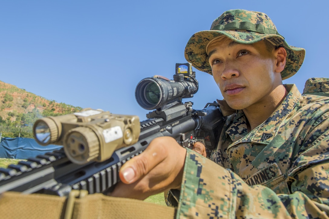 A Marine holds a weapon and looks into the distance.