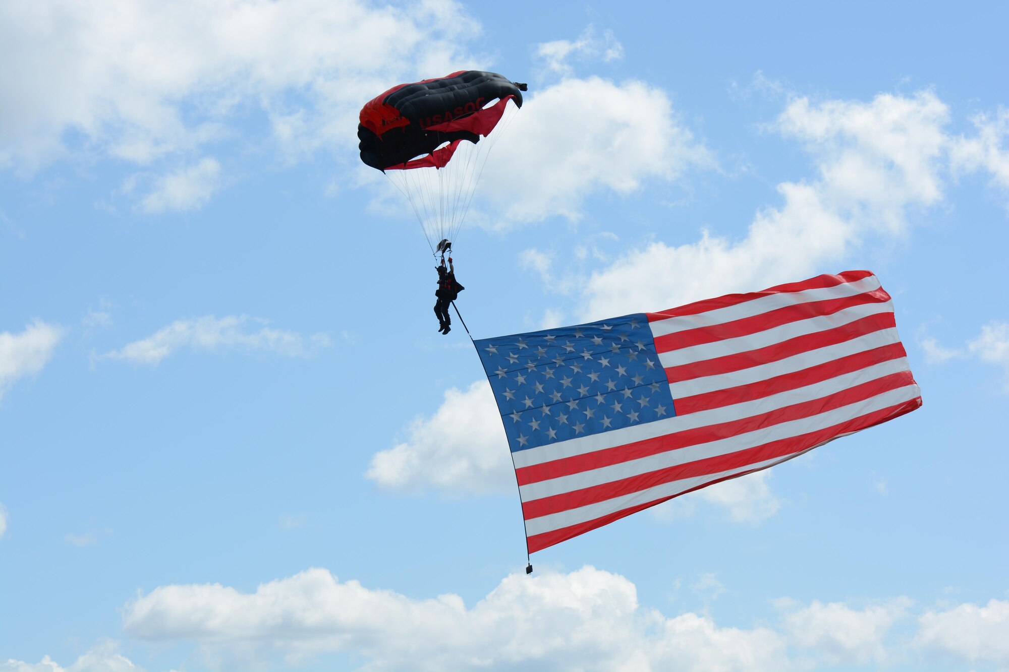 A member of the Black Daggers U.S. Army Special Operations Command parachute demo team displays the American flag on his descent August 13, 2017, at the 2017 Westfield International Air Show at Barnes Air National Guard  Base in Westfield, Mass.