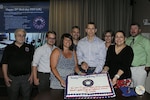 Group of civilians facing viewer, holding sheet cake