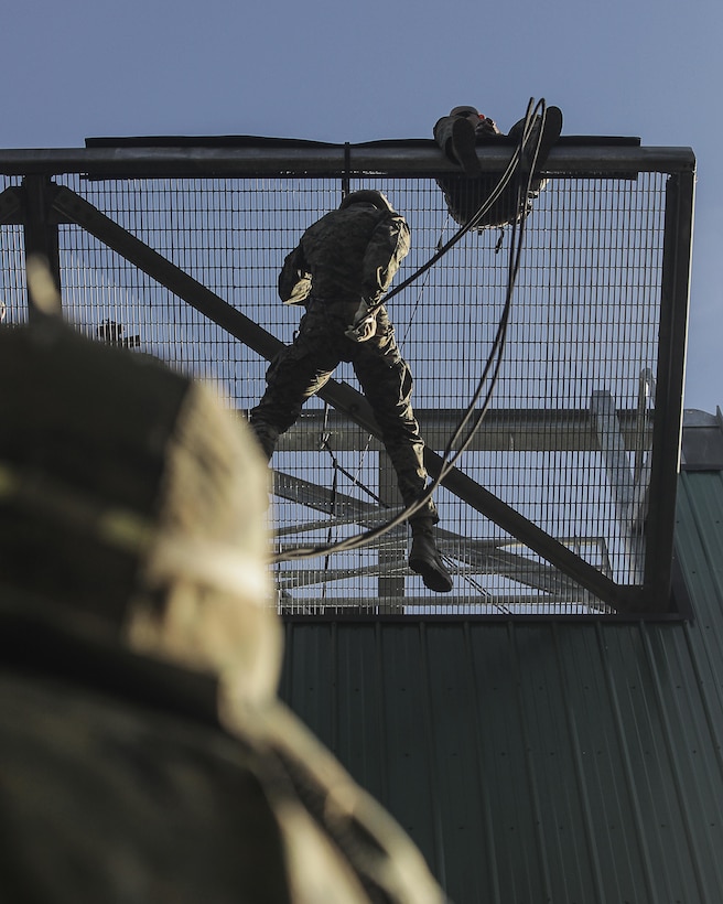 U.S. Marine Corps Corporal Lucas Anderson, 3rd Team Leader, 2nd Squad, with 2nd Battalion, 23rd Marine Regiment, 4th Marine Division, Marine Forces Reserve, drops down from a simulated helo pad during the helo, insertion and mountain rappelling exercise on Camp Carroll, Joint Base Elmendorf-Richardson, Alaska, Aug. 4, 2017.