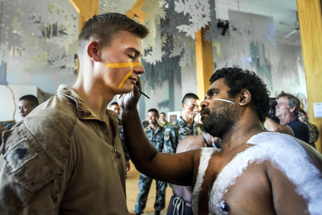 An Australian paints the face of a U.S. Marine.