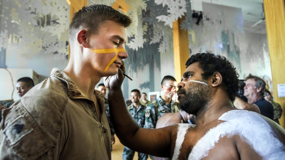 An Australian paints the face of a U.S. Marine.