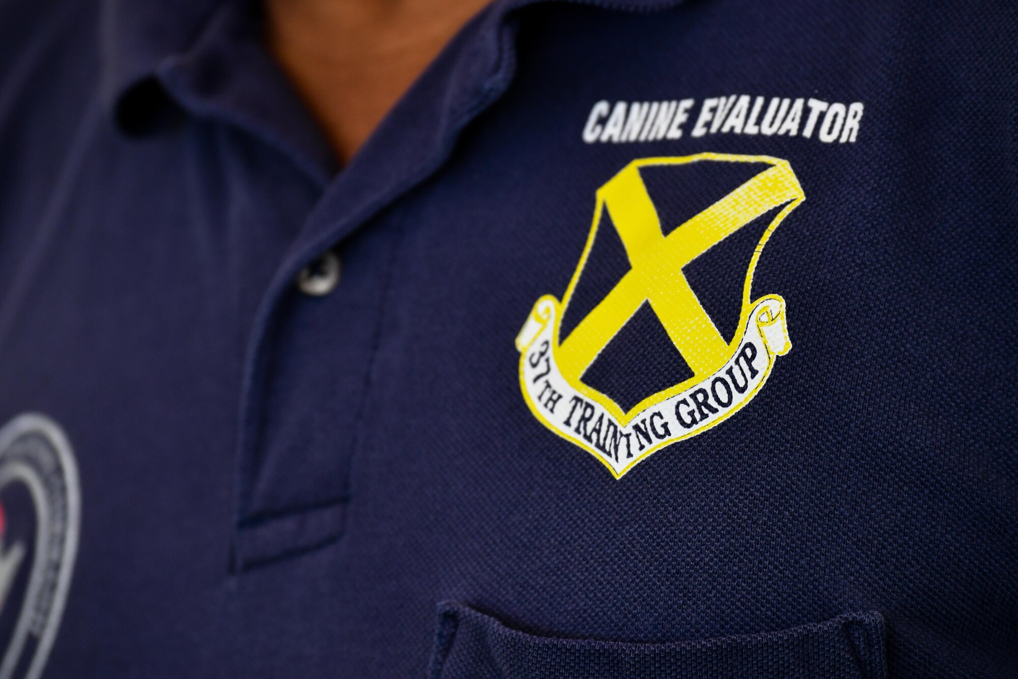 Mr. Oscar Clayton, 341st Training Squadron senior military working dog evaluator, wears a shirt with the 37th training group logo during a patrol dog certification evaluation at Barksdale Air Force Base, La., Aug. 11, 2017. The 341st Training Squadron provides military working dogs to the Army, Navy, Air Force and the Marine Corps.