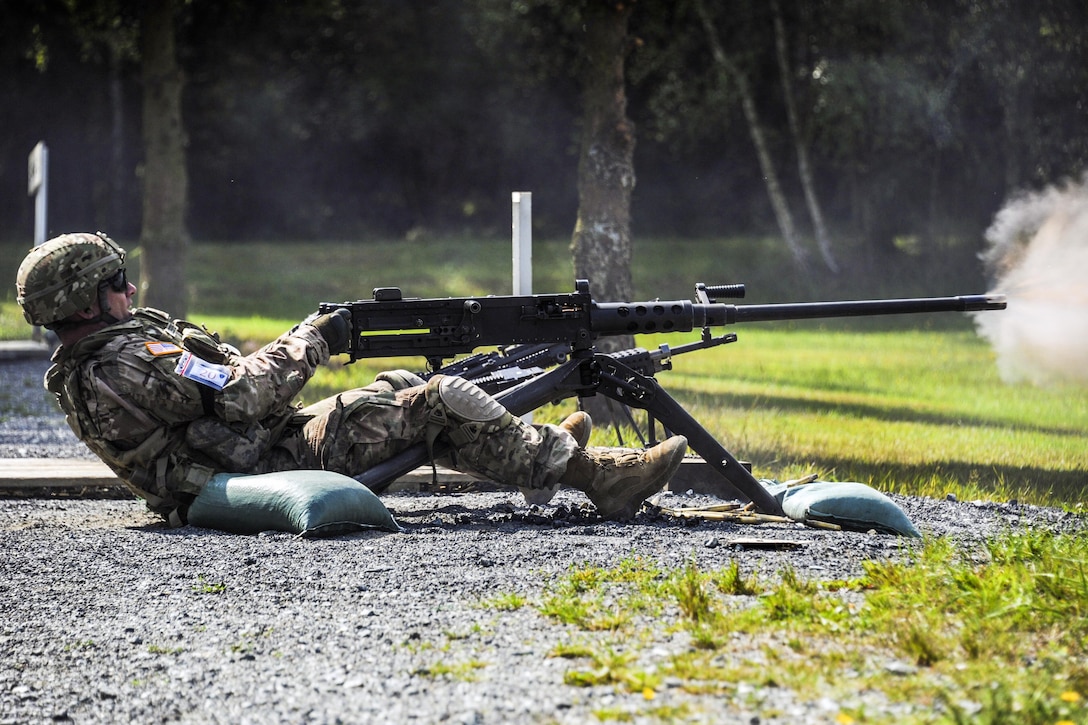 A sitting soldier leans back and fires a machine gun.