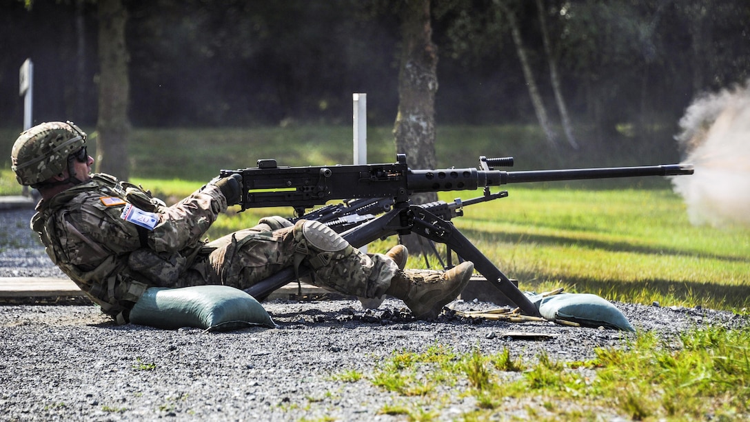 A sitting soldier leans back and fires a machine gun.