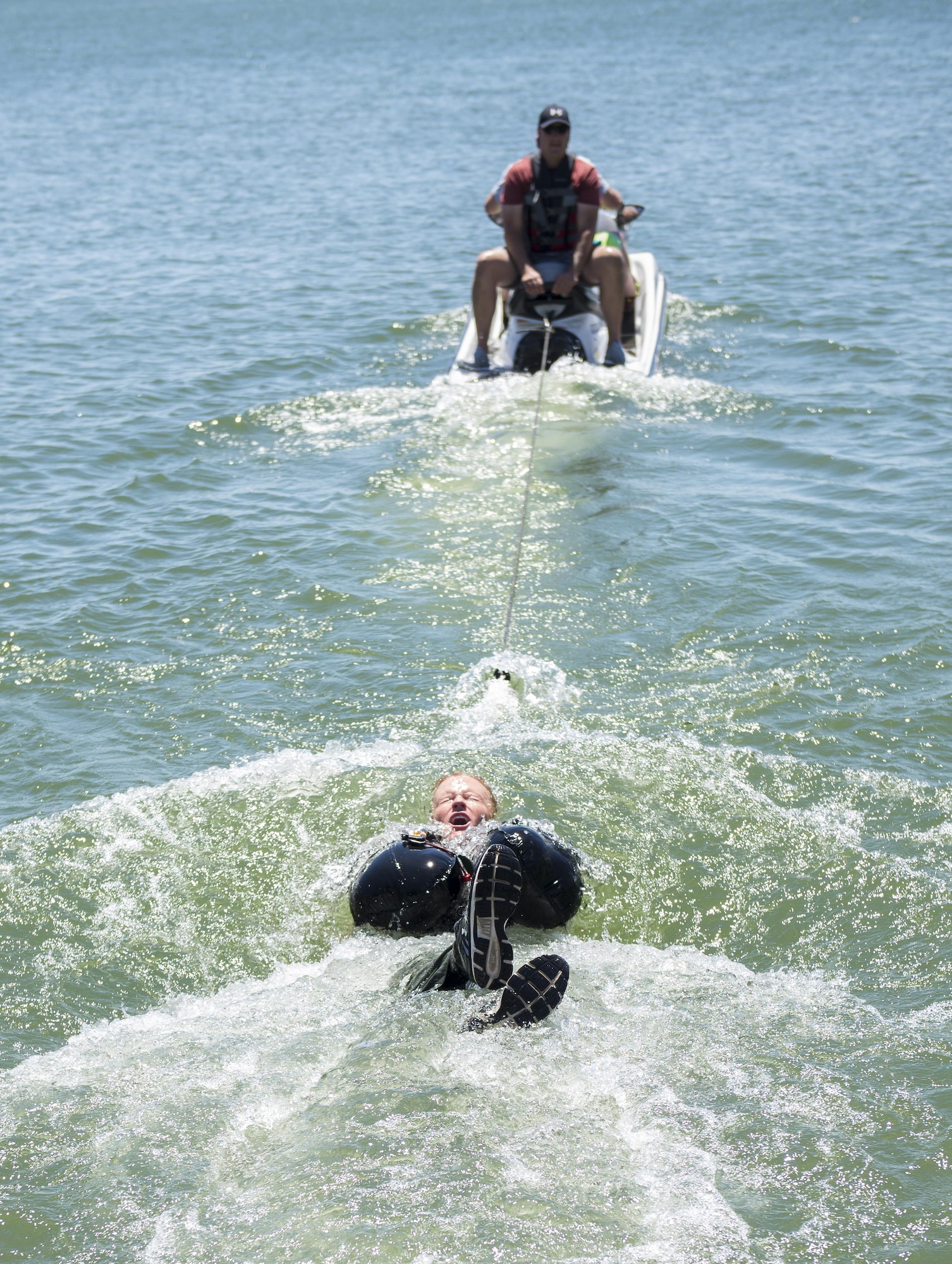 A pilot is dragged behind a jet ski during water survival training July 11, 2017, at CJ Strike Reservoir, Idaho. This portion of training teaches proper technique when hitting the water and being dragged by an open parachute. (U.S. Air Force photo by Airman 1st Class Jeremy D. Wolff/Released)