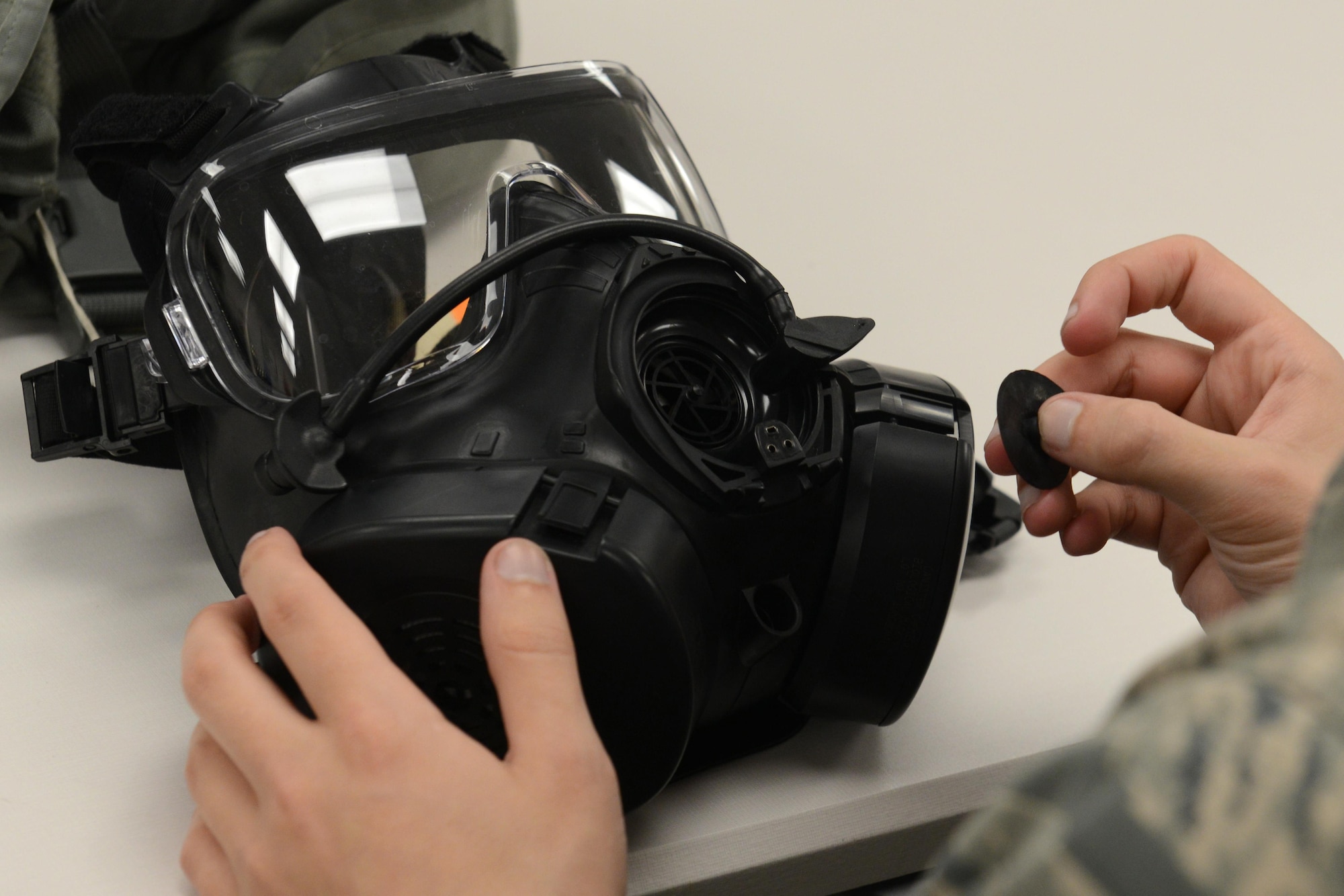An Airman inspects his gas mask during a Chemical, Biological, Radiological, and Nuclear defense survival skills training class hosted by the 773d Civil Engineer Squadron emergency management flight at Joint Base Elmendorf-Richardson, Alaska, Aug. 22. The two-hour CBRN class reminds Airmen of the various equipment and proper procedures used pre- and post-attack, and puts the Airmen’s knowledge to the test with an application of this information in full Mission Oriented Protected Posture gear.