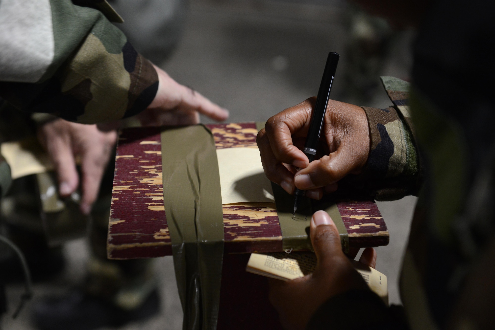 Airmen tape and write the date on a simulated M-9 post during a Chemical, Biological, Radiological, and Nuclear defense survival skills training class hosted by the 773d Civil Engineer Squadron emergency management flight at Joint Base Elmendorf-Richardson, Alaska, Aug. 22. The two-hour CBRN class reminds Airmen of the various equipment and proper procedures used pre- and post-attack, and puts the Airmen’s knowledge to the test with an application of this information in full Mission Oriented Protected Posture gear.