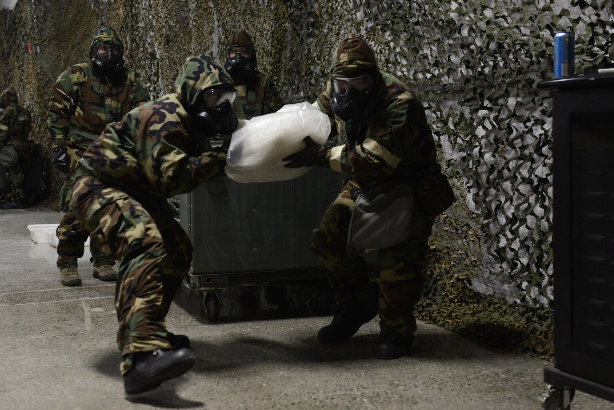 Two Airmen quickly dispose of a simulated contaminated cover during a Chemical, Biological, Radiological, and Nuclear defense survival skills training class hosted by the 773d Civil Engineer Squadron emergency management flight at Joint Base Elmendorf-Richardson, Alaska, Aug. 22. The two-hour CBRN class reminds Airmen of the various equipment and proper procedures used pre- and post-attack, and puts the Airmen’s knowledge to the test with an application of this information in full Mission Oriented Protected Posture gear.