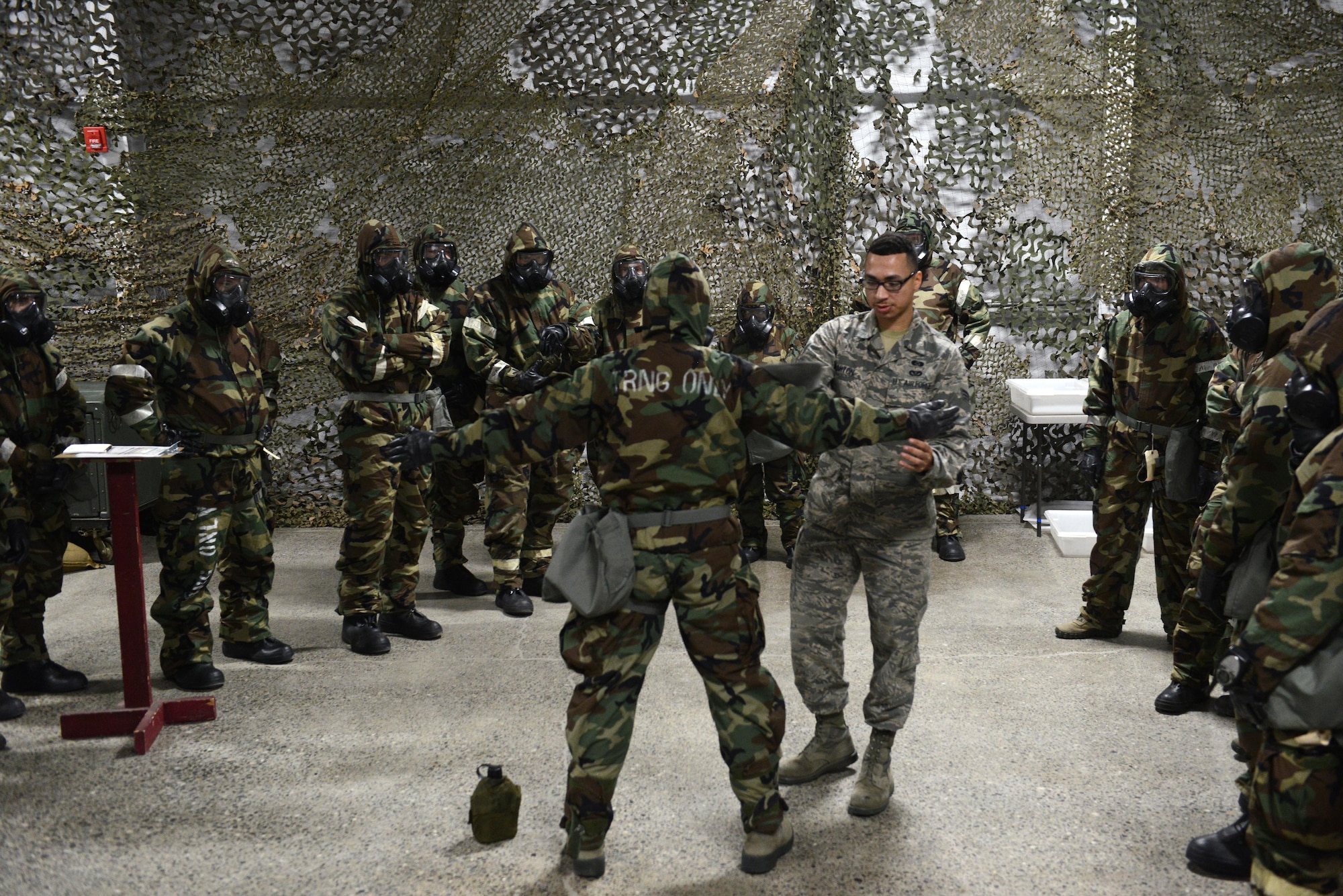 Senior Airman Alexander Barton (right), 773d Civil Engineer Squadron emergency management trainer, demonstrates how to decontaminate someone with a charcoal pad as an absorbent material in a pat-pat-swipe maneuver during a Chemical, Biological, Radiological, and Nuclear defense survival skills training class at Joint Base Elmendorf-Richardson, Alaska, Aug. 22. The two-hour CBRN class reminds Airmen of the various equipment and proper procedures used pre- and post-attack, and puts the Airmen’s knowledge to the test with an application of this information in full Mission Oriented Protected Posture gear.