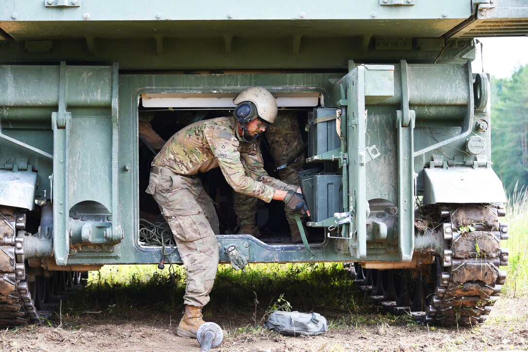 Soldiers prepare an artillery vehicle for an exercise in a field.