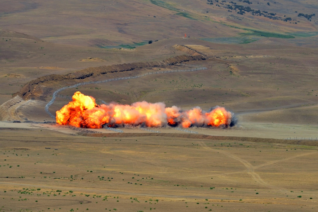 A line of smoke and fire rises from the terrain.