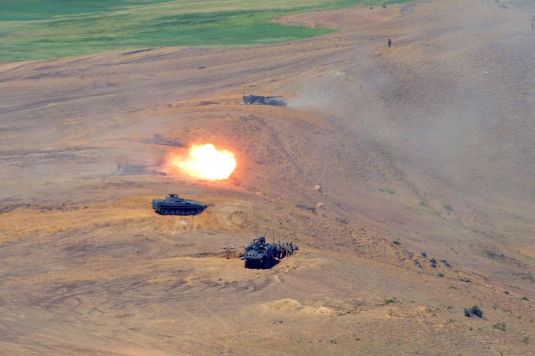 Military vehicles are near an explosion.