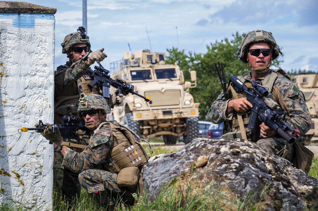 Three service members hold weapons and maneuver during a training exercise.
