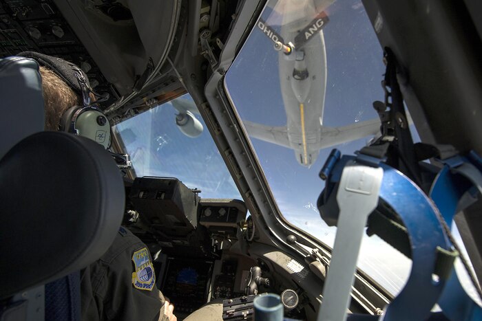 A pilot looks though a windshield at another plane.