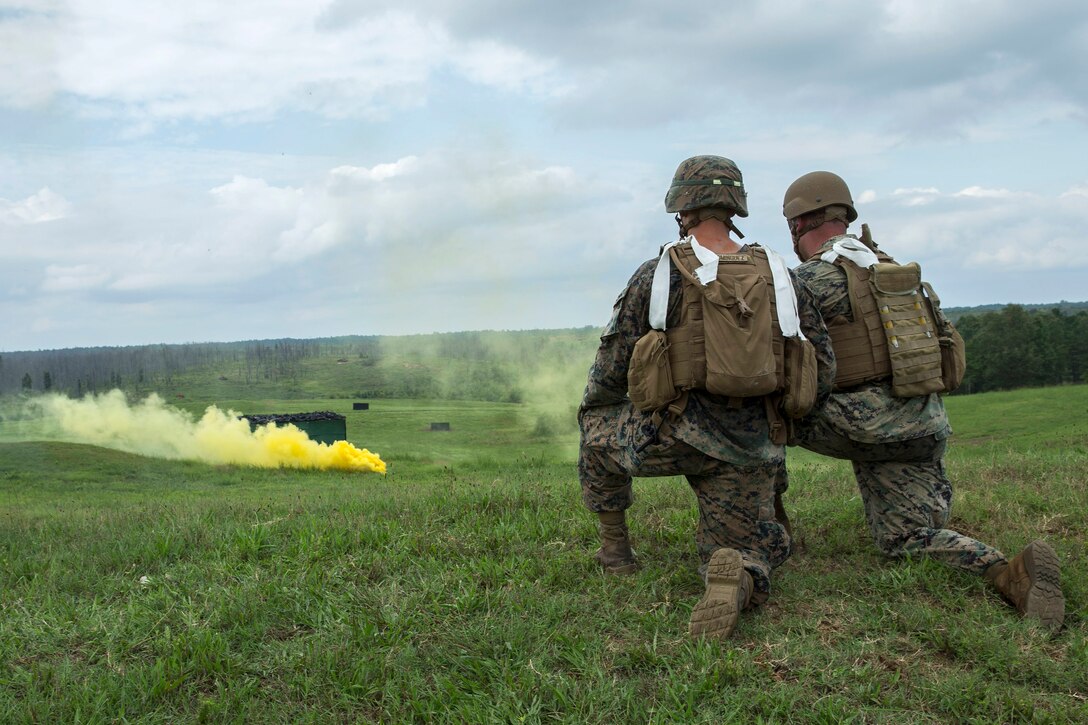 Marines watch smoke grenades downrange.