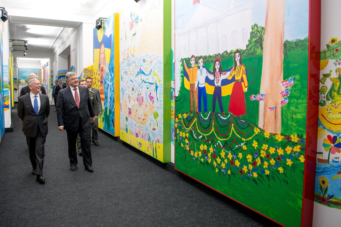 Defense Secretary Jim Mattis walks with the Ukrainian president down a colorfully painted hallway.