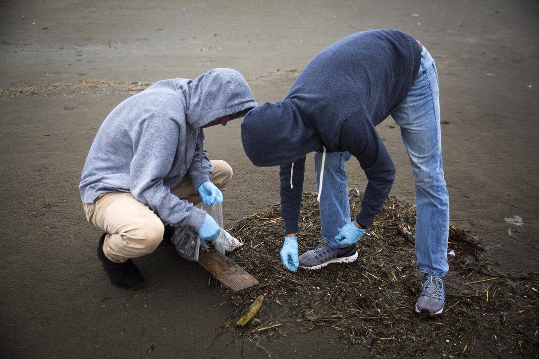 Two U.S. Marines pick up trash at Miss Veedol Beach, Misawa, Japan, August 19, 2017, during Exercise Northern Viper 2017. Marines, Sailors, Airmen banded together with Misawa City employees to participate in the beach cleanup. NV17 tests the interoperability and bilateral capability of the Japan Ground Self-Defense Force and U.S. Marine Corps forces to enhance regional cooperation between participating nations to collectively deter security threats. The Marines are assigned to Marine Aircraft Group 36, 3rd Marine Aircraft Wing. (U.S. Marine Corps photo by Lance Cpl. Andy Martinez)