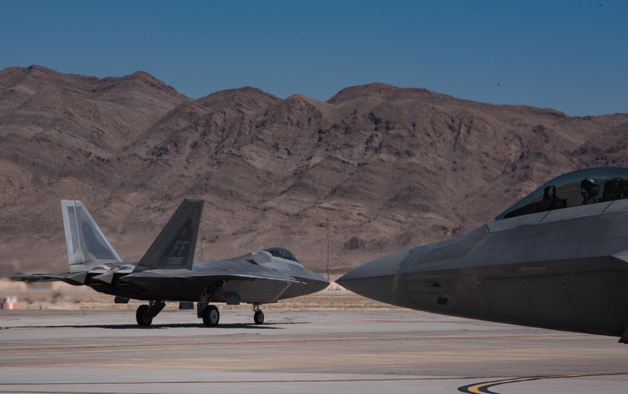 Two U.S. Air Force F-22 Raptors taxi to takeoff during Red Flag 17-4 at Nellis Air Force Base, Nev., Aug. 17, 2017. The F-22 on the left is Capt. Mach, 94th Fighter Squadron F-22 Raptor pilot, mission commander for this launch. (U.S. Air Force photo by Staff Sgt. Carlin Leslie)