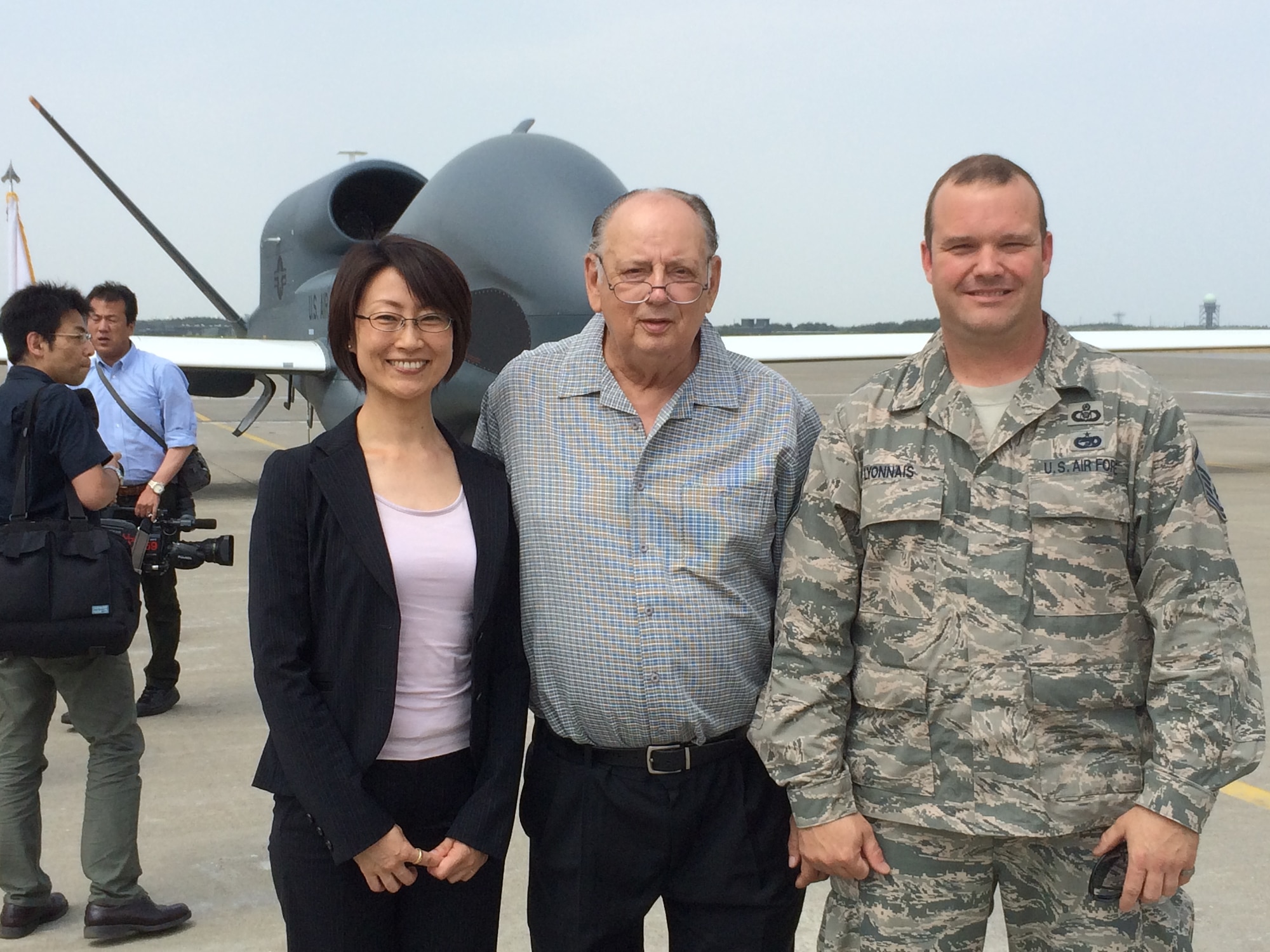 Mike Bishop standing with Ms. Makiko Oshima, Deputy Director, Treaties Division, Ministry of Foreign Affairs, and Master Sgt. Steven Lyonnais, Misawa Air Base’s Airfield Manager, pose for a photo in front of an RQ-4 Global Hawk on the flight line of Misawa AB, May 30, 2014. (Courtesy Photo)