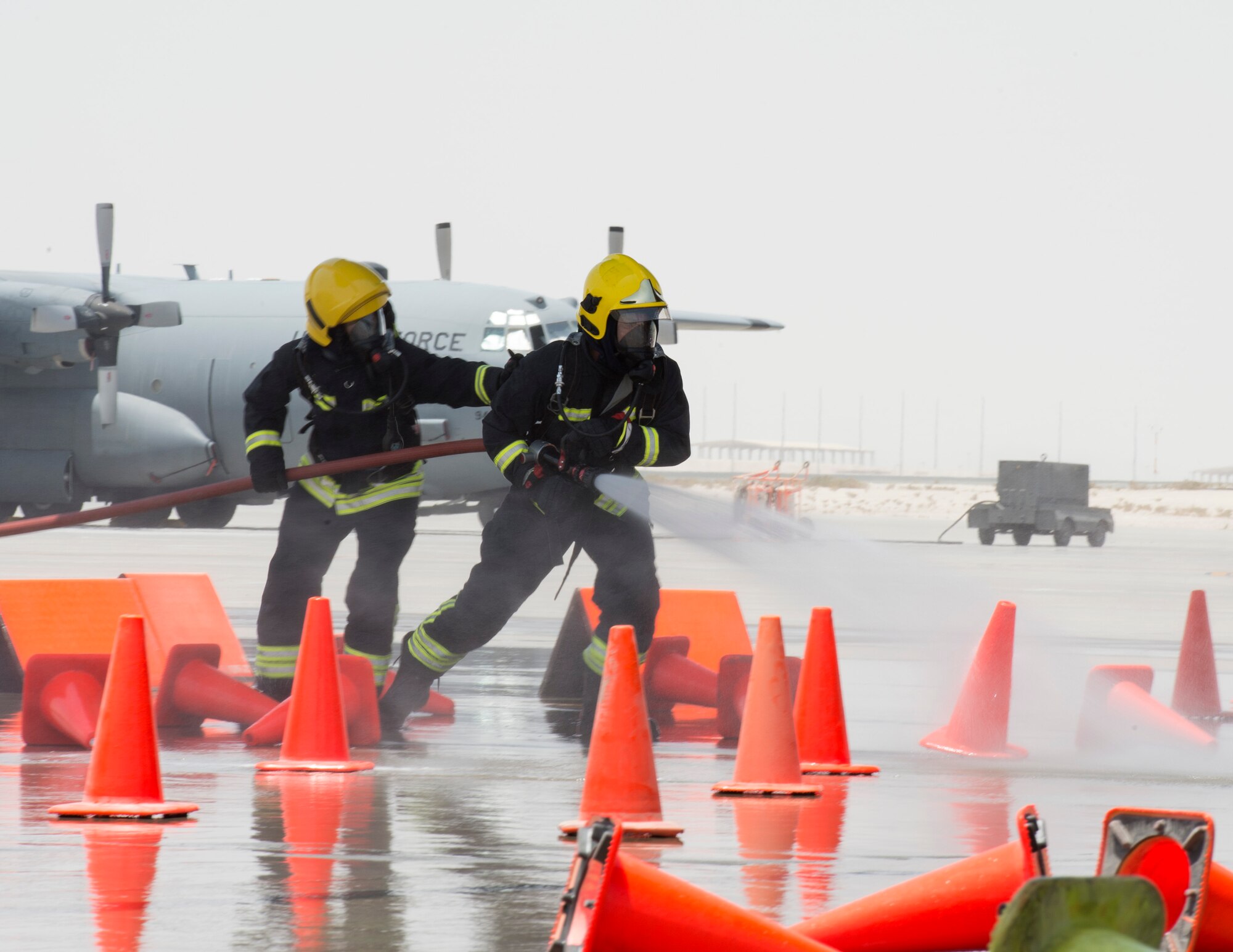 Firefighters with the Qatar Emiri Air Force Fire Department hose down cones during a joint C-130 Hercules aircraft exercise at Al Udeid Air Base, Qatar, Aug. 1, 2017.