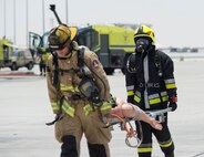 Firefighters with the 379th Expeditionary Civil Engineer Squadron’s Fire and Emergency Services Flight, left, and the Qatar Emiri Air Force Fire Department carry a simulated patient during a joint C-130 Hercules aircraft exercise at Al Udeid Air Base, Qatar, Aug. 1, 2017.