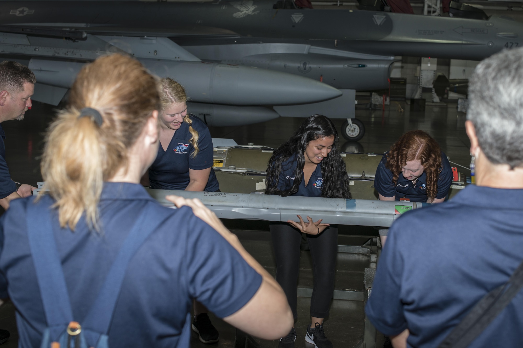 High school students visiting Misawa City with a delegation from Wenatchee Valley, Washington, attempt to lift an F-16 Fighting Falcon’s missile during their tour of Misawa Air Base, Japan, Aug. 24, 2017.