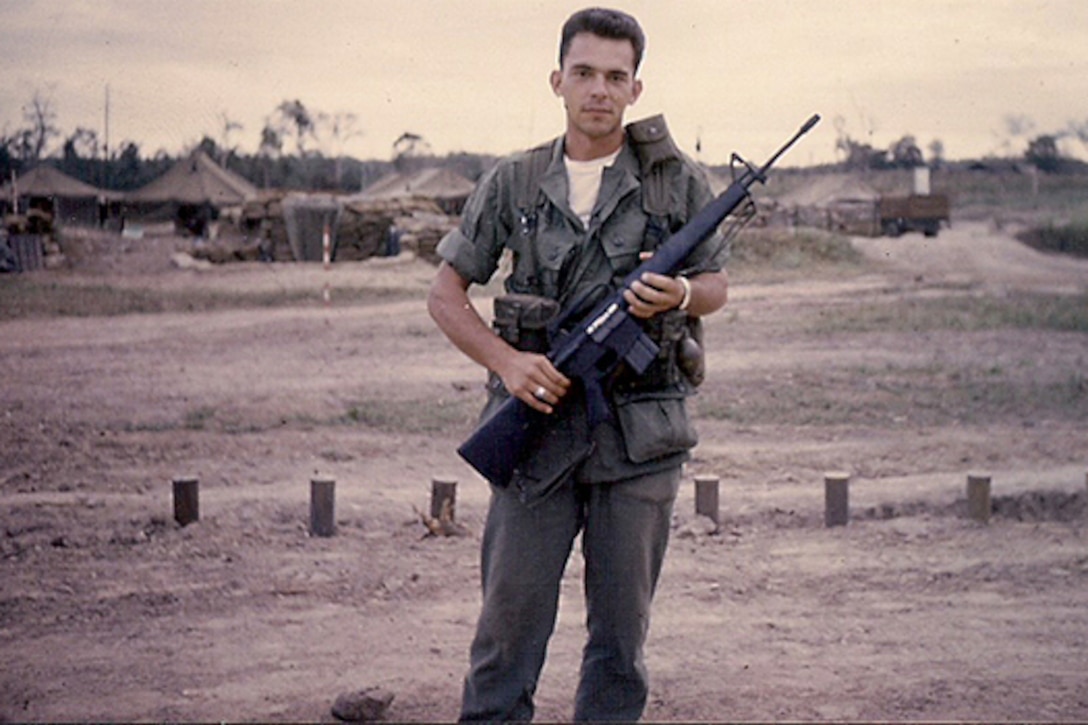 A soldier stands holding a rifle in Vietnam.