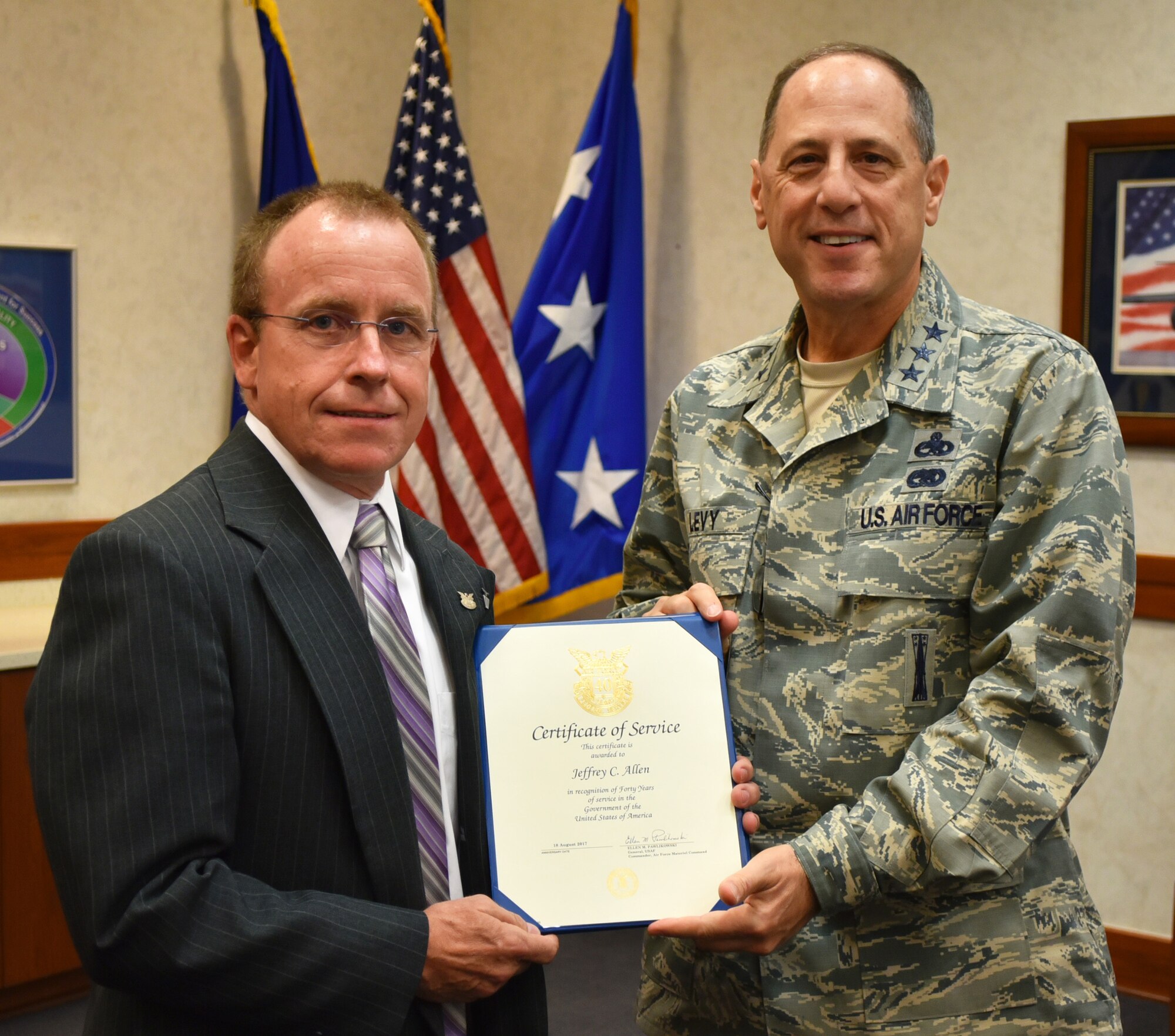 Lt. Gen. Lee K. Levy II, Air Force Sustainment Center commander, presents Jeffrey Allen with a Certificate of Service, recognizing his executive director for 40 years of federal service prior to his weekly staff meeting Aug. 10 in Bldg. 3001.