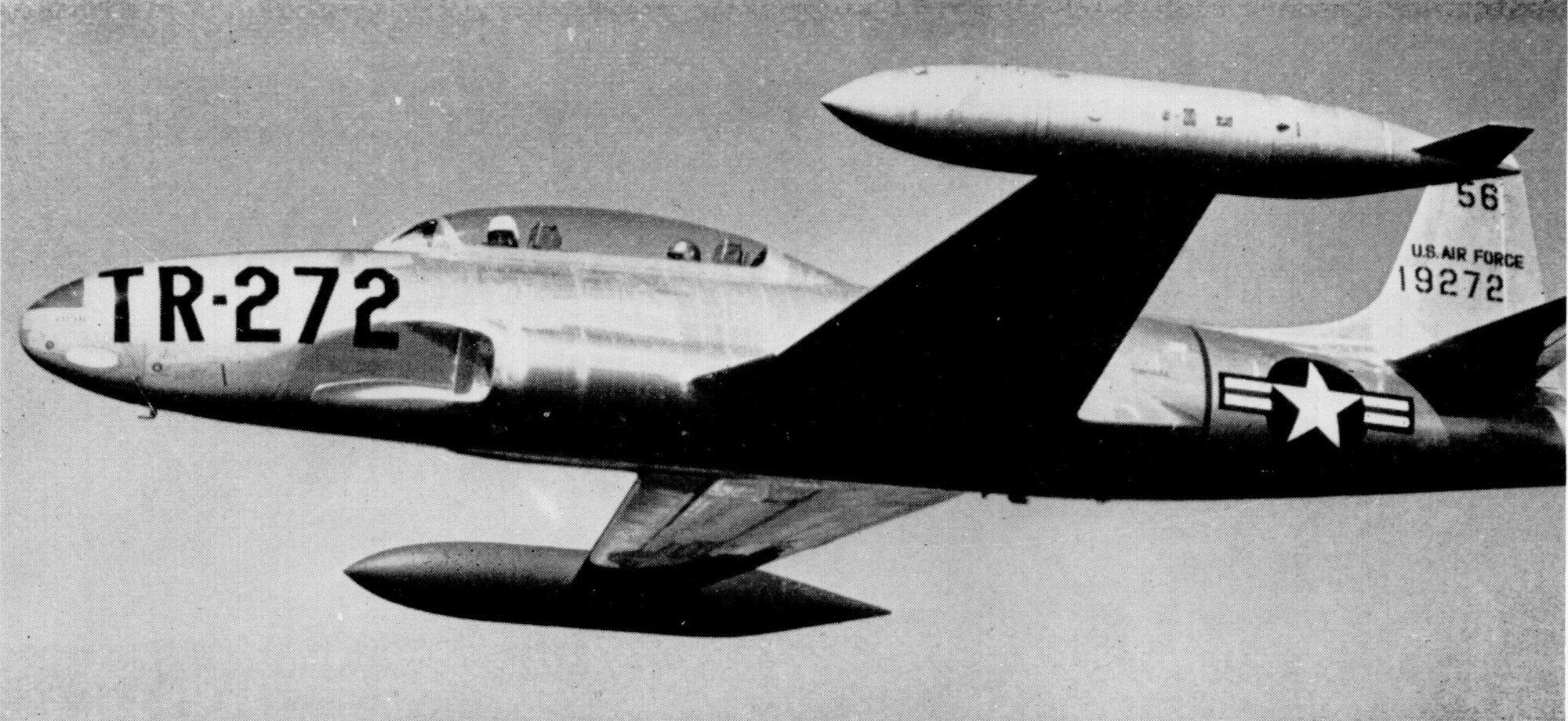 A T-33A Shooting Star shown in-flight in standard training configuration with wingtip tanks wearing natural-metal and early training command markings.