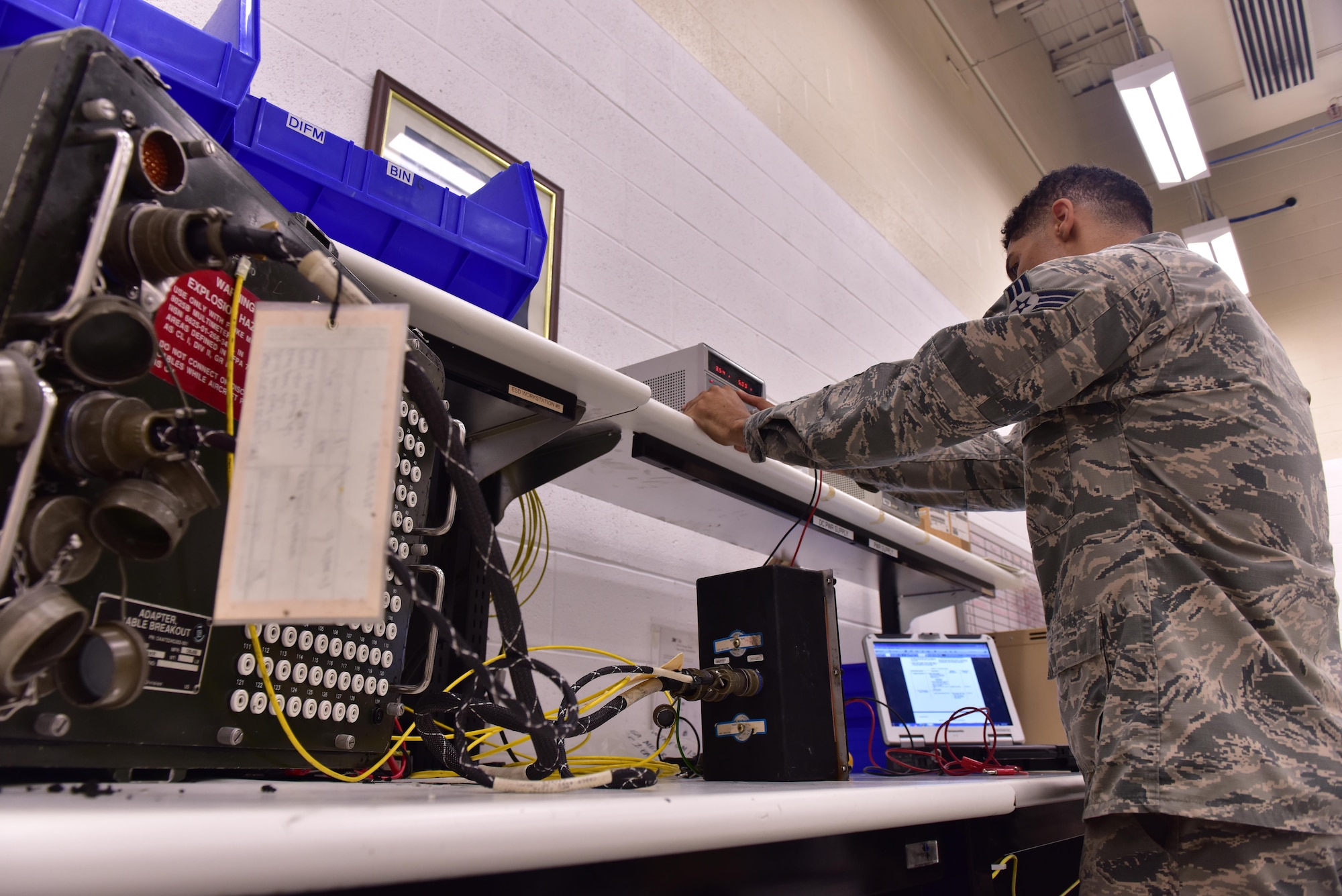 U.S. Air Force Senior Airman Christian Anthony, an electrical and environmental specialist assigned to the 509th Maintenance Squadron, connects an overhead lighting control unit onto a breakout box at Whiteman Air Force Base, Mo., Aug. 3, 2017.