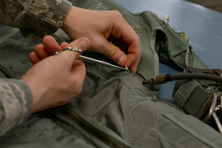 U.S. Air Force Senior Airman Thomas Cadwell, an aircrew flight equipment technician assigned to the 509th Opera-tions Support Squadron, inspects the oxygen bottle at-tached to a parachute at Whiteman Air Force Base, Mo., Aug. 21, 2017. If a pilot ejects at a high altitude with less oxygen, he will need to pull the oxygen bottle cord which will release oxygen through a tube connected to his helmet.