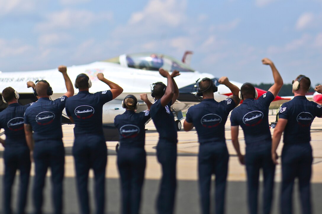 A line of airman wave to a Thunderbird aircraft before a practice show
